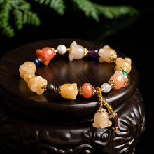  Natural Xinjiang Gold Silk Magnolia Bracelet with Jinsi Jade and orchid beads on black display.