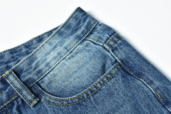 Close-up of blue low waist jeans with distressed and washed details.