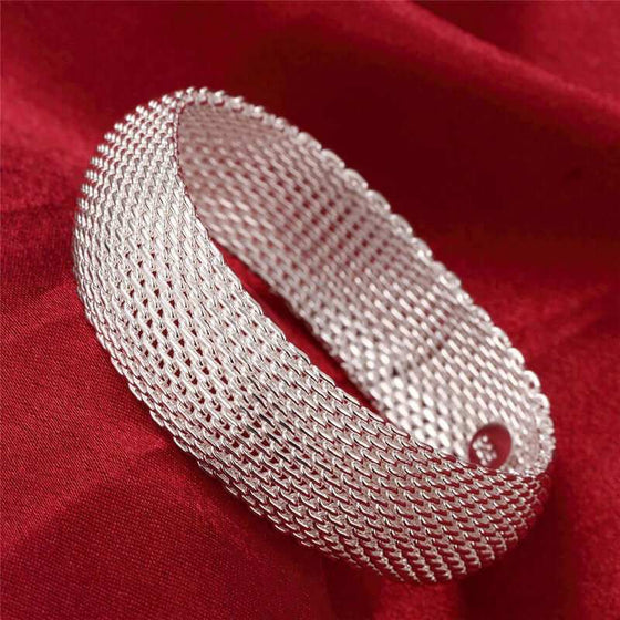 Women's silver mesh bracelet on red fabric background.