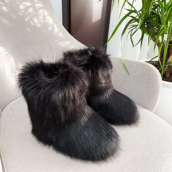 Women's closed toe fluffy plush snow boots in black, showcasing luxurious faux fur on a cozy chair with greenery.