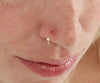 Sterling silver diamond body piercing jewelry nose ring in geometric shape, worn by a woman.