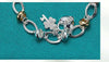 Silver Love Key Bracelet with love-shaped charm and ethnic design on teal background.