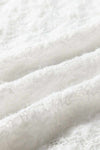 Close-up of white lace fabric texture on a mock neck long sleeve top.