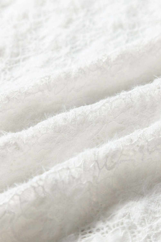 Close-up of white lace fabric texture on a mock neck long sleeve top.