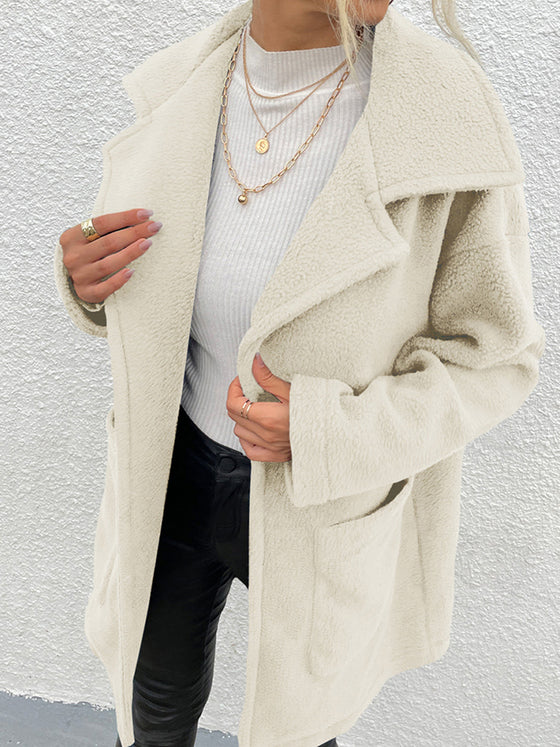 Shiny dropped shoulder coat with pockets in white polyester, styled over a white top and black pants.