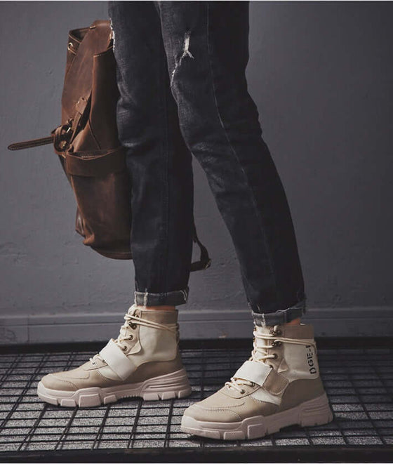 High quality fashion winter men's boots with a beige design, paired with dark jeans and a brown bag.