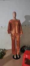 Polka dot printed long-sleeved trousers suit in orange with loose shoulder design on a mannequin.