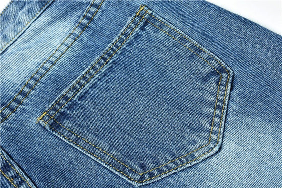 Close-up of the back pocket on blue low waist jeans with distressed and washed details.