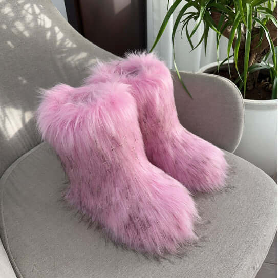 Women's pink fluffy plush snow boots displayed on a chair, perfect for cozy winter Fashion.