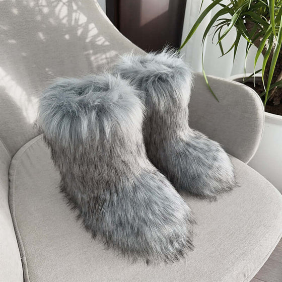 Women's gray fluffy plush snow boots resting on a chair, showcasing soft imitation fur and cozy design.