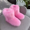 Women's pink fluffy plush snow boots on a cozy chair, perfect for winter warmth and style.