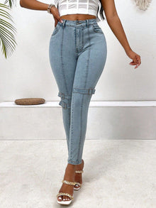  Decorative buckle skinny jeans in light blue with pockets, worn with a cropped top and stylish heels.