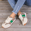 Contrast round toe flat sneakers with green accents, stylishly worn with ripped jeans on a wooden surface.