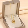 Gold chain necklace with heart-shaped titanium steel pendant in a jewelry box.