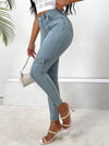 Decorative buckle skinny jeans with pockets, stylishly paired with heels and a crop top against a minimalist background.