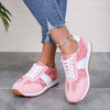 Contrast round toe flat sneakers in pink and white, styled with ripped jeans for a trendy look.